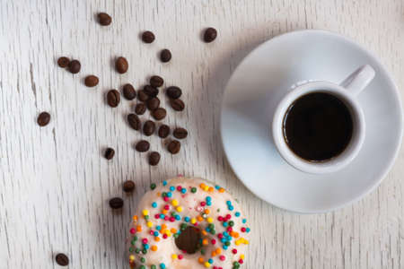 Cup of coffee and donuts with sprinkles on a wooden backgroundの写真素材