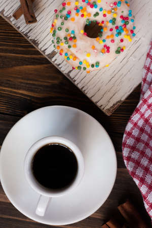 Cup of coffee and donut on wooden background, top viewの写真素材