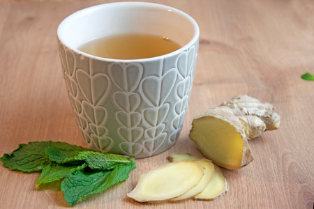 Cup of tea on wooden board with mint and ginger