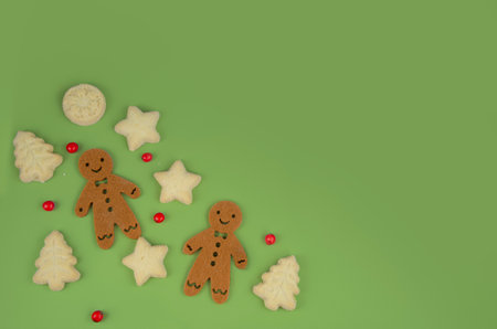 Gingerbread men and biscuits on green background, red berriesの写真素材
