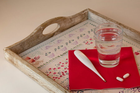 Tray with water glass, pills and thermometer, red and white