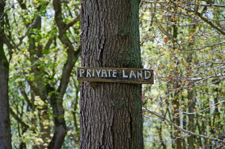 Private land hand painted sign mounted on a tree trunk, forest back dropの写真素材