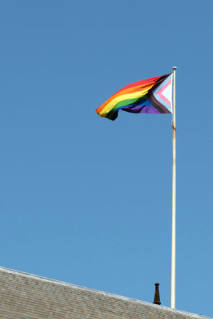 Rainbow flag on top of roof blowing in the wind