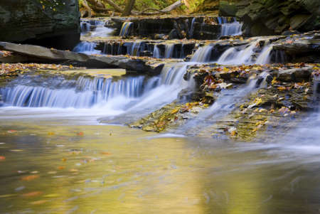 A series of small waterfalls emptying into a pool in autumn.の写真素材