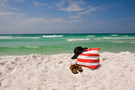 A beach bag , hat and sandals lying on the beach.の写真素材