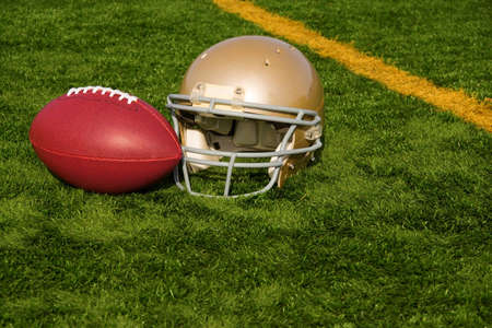 An American football helmet and ball on a field by the goal lineの写真素材