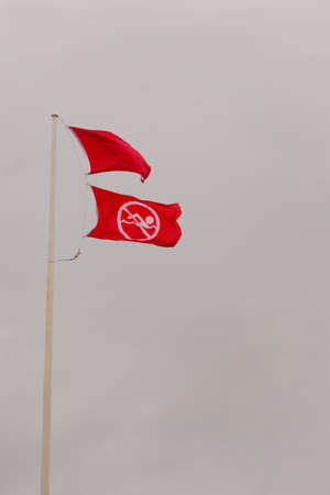 Red warning flags against a gray stormy sky.の写真素材