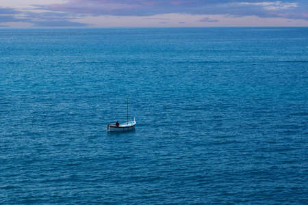 A lone fishermanin a small boat in the ocean