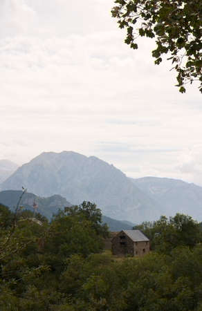 View of a landscape in Pyrenees with a house on a plain between high mountain vegetationの写真素材