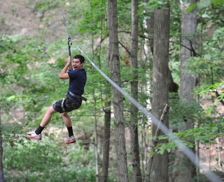 Teen boy ziplining in the woods