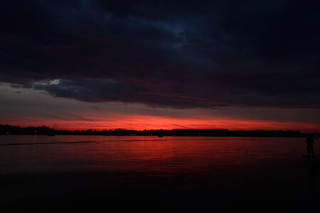 Evening fiery red sunset colors and clouds over Lake James in Angola, Indiana USA.の写真素材