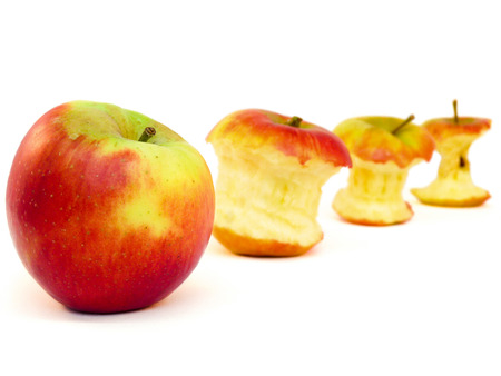 Apples and apple cores lying in a row isolated on white backgroundの写真素材
