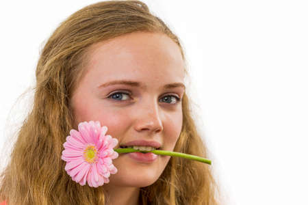Face of european teenage girl with flower in her mouth isolated on white backgroundの写真素材