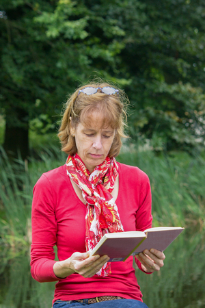 Woman reading book in green natureの写真素材