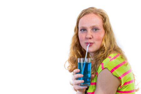 Dutch redhead teenage girl drinking blue soda with straw isolated on white backgroundの写真素材