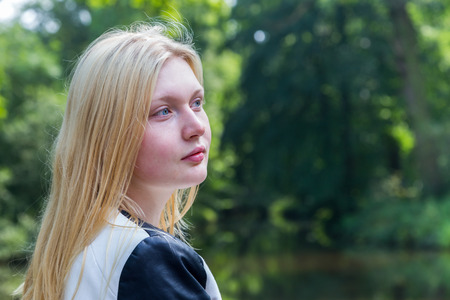 Head of blond dutch teenage girl with water and trees in parkの写真素材