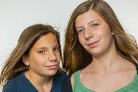 Portrait of two caucasian teenage girls with long blown hair isolated on white backgroundの写真素材