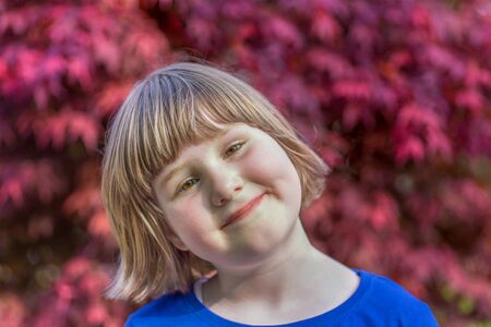 Young caucasian girl with red maple leaves as background in autumnの写真素材