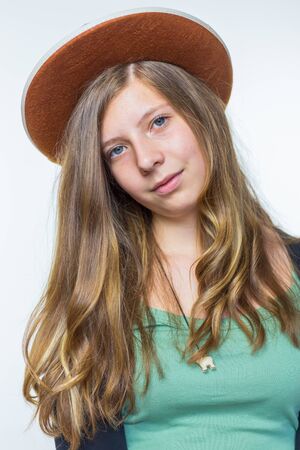 Blonde european teenage girl with long blonde hair wearing brown hat isolated on white backgroundの写真素材
