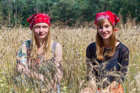Two caucasian teenage girls sitting in cropland or corn fieldの写真素材