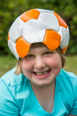 Young european girl wearing leather football on head is laughing at cameraの写真素材