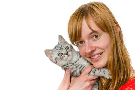 European redhead teenage girl hugging young black silver tabby cat isolated on white backgroundの写真素材