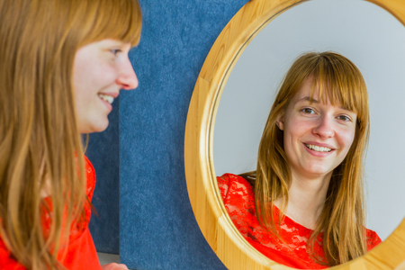 Portrait of caucasian redhead teenage girl looking in mirrorの写真素材