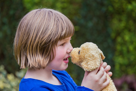 young caucasian girl hugging stuffed dog against her noseの写真素材