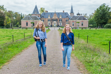 Two caucasian teenage girls walking away from castle in the netherlandsの写真素材