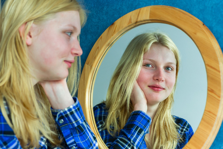Blonde teenage dutch girl looking in mirrorの写真素材