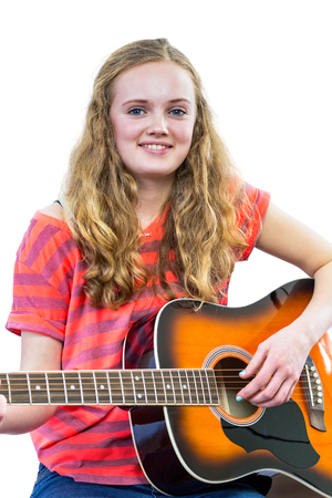 European teenage girl with long hair playing guitar isolated on white backgroundの写真素材