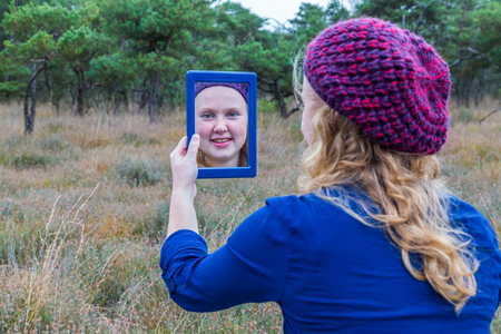 Dutch teenage girl holding mirror in nature and looking at herselfの写真素材
