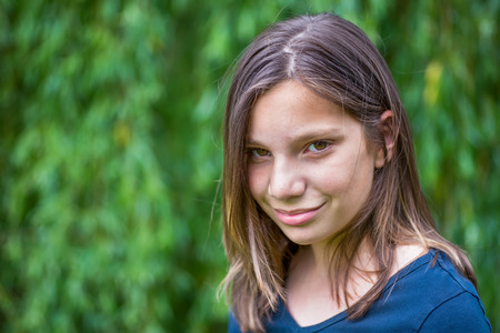 Portrait of caucasian teenage girl in front of green willowの写真素材