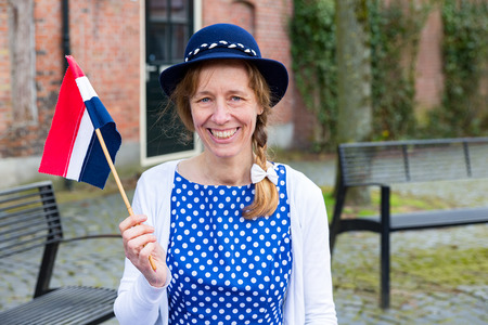 Caucasian middle aged woman dressed in blue clothes celebrating liberation day with dutch flagの写真素材