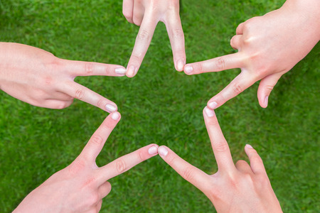 Five hands of teens making starshape together