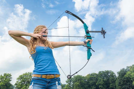 Blond caucasian girl shooting with arrow and bowの写真素材