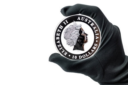 Hand in black glove holding large silver 10 dollars coinの写真素材