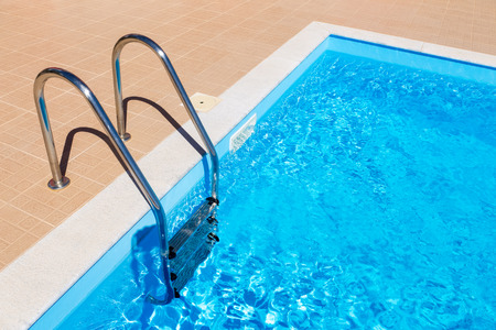 water in blue swimming pool with steps in summer seasonの写真素材