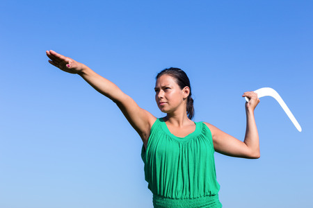 european woman throwing white boomerang in blue skyの写真素材