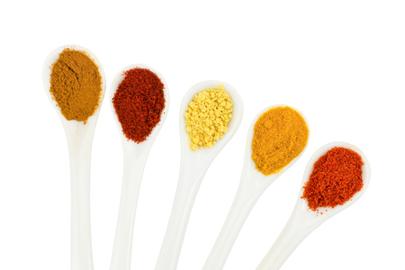 Various seasoning spices on porcelain spoons isolated on white backgroundの写真素材