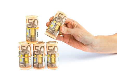 Hand putting down rolls of euro money isolated on white background