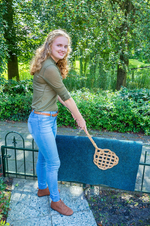 Caucasian teenage girl beating door mat with carpet beaterの写真素材