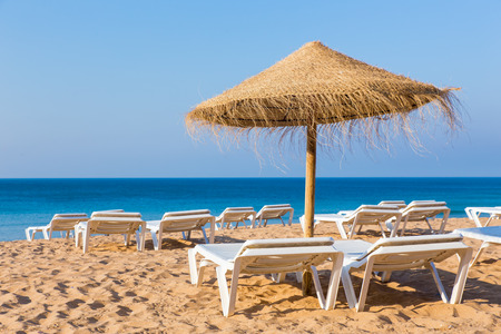 Wicker beach parasol with beach beds at blue seaの写真素材