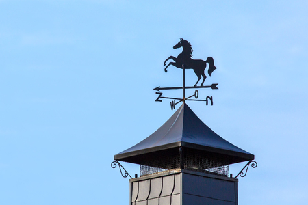 Black metal horse on weather vane standing on chimney capの写真素材