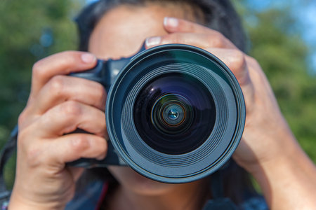 Close up young woman photographing with camera outside