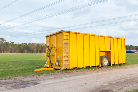 Large yellow cow manure tank parked in meadowの写真素材