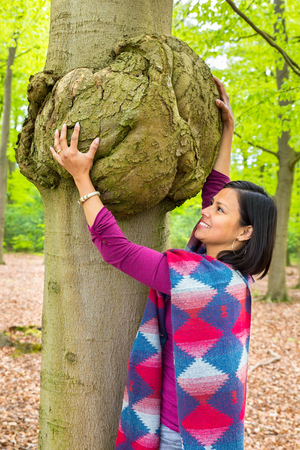 Colombian woman holding cancerous tumor on beech tree trunkの写真素材
