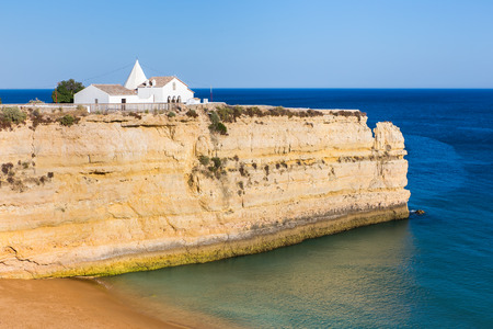 Small white portuguese church on steep rock in blue seaの写真素材