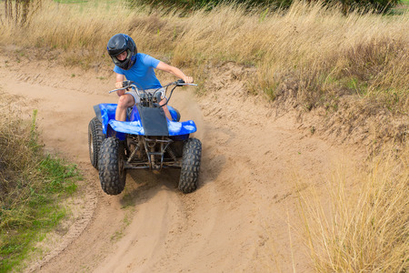 Young european man driving quad through the bend