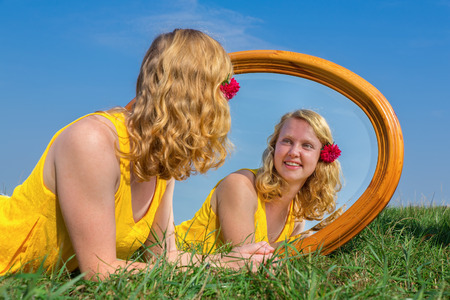 Young red-haired dutch woman lying in grass with mirrorの写真素材